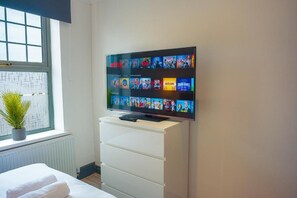 A television mounted on a wall displaying various movie titles. - Crwys Road 4-Bed Apartment, Near City Centre, Great for Long Stays (Cardiff)