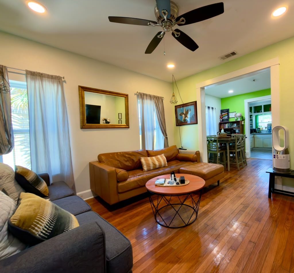 A living room with a brown sofa, a round coffee table, and a ceiling fan.