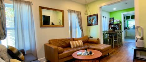 A living room with a brown sofa, a round coffee table, and a ceiling fan.