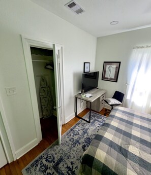 A bedroom with a bed, a desk, a television, and a wardrobe. - Cozy coastal cottage just a few steps from the ocean (Galveston)
