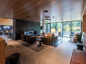 Ein modernes Interieur mit Holzboden, einem Flachbildfernseher, einer Couch, einem Couchtisch und einem Essbereich mit Stühlen und einer Lampe.