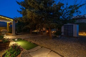 Ein Garten mit Pool, einer überdachten Sitzgelegenheit und einem Gartenhaus.