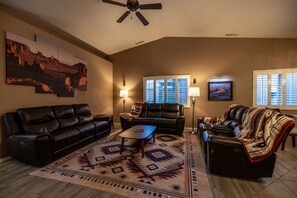 Ein Wohnzimmer mit Ledersofas, einem Couchtisch, einem gemusterten Teppich und Wandbildern.
