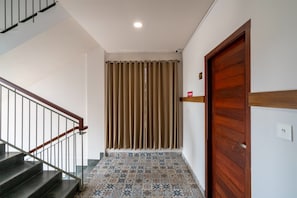 A staircase with a metal railing leading to a room with patterned tile flooring and a wooden door.