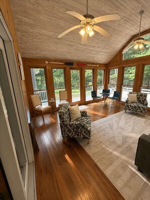 A spacious room with a wooden floor, large windows, and a ceiling fan. - Peaceful Moultonborough Getaway | Sleeps 14 (Moultonborough)