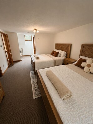 Ein Hotelzimmer mit zwei Betten, einem Holzkopfteil, einem kleinen Nachttisch und Teppichboden.