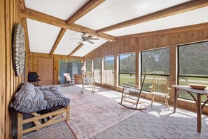 Ein Holzinnenraum mit Deckenventilator, einer Bank und einem Tisch mit einer Schüssel.