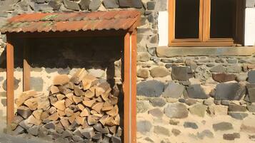 Un edificio de piedra con estructura de madera y una ventana con cortinas de encaje.
