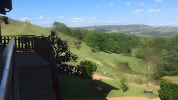Un balcon offrant une vue sur un paysage verdoyant et des collines lointaines.