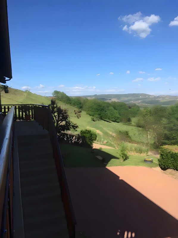 A balcony with a view of a green landscape and distant hills.