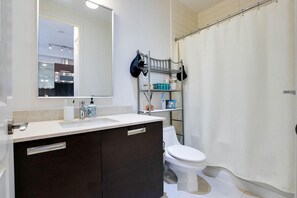 A modern bathroom with a white sink, dark cabinets, a toilet, and a shower curtain. - Yorkville Upscale 1bed1bath | Pool | Gym (Toronto)