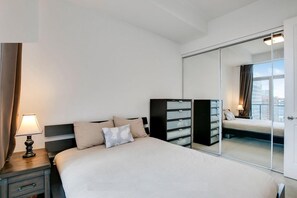 A bedroom with a bed, bedside tables, a lamp, a wardrobe, and a sliding glass door leading to a balcony. - Yorkville Upscale 1bed1bath | Pool | Gym (Toronto)