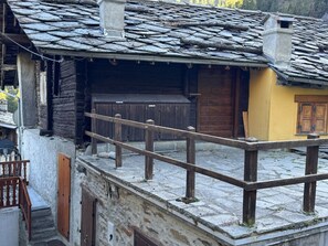 Ein traditionelles Holzgebäude mit Steinziegeldach, einem Holzbalkon und einer gelben Wand.