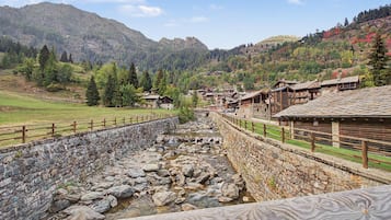 A stone-lined water channel with wooden buildings on one side and a mountainous backdrop.