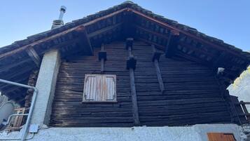 Eine rustikale Holzhütte mit geneigtem Dach, Schornstein und einem Fenster mit Fensterläden.