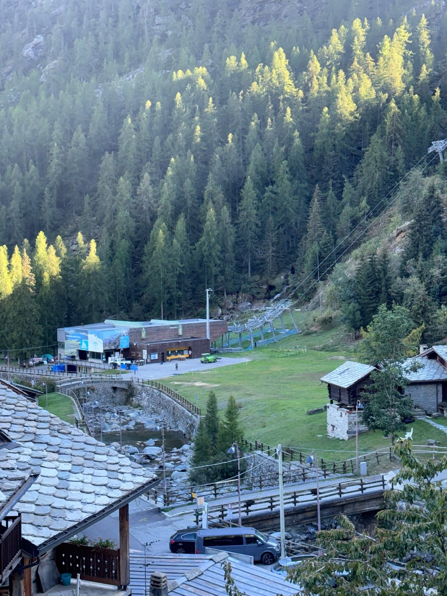 Zona montuosa con un edificio che sembra una locanda o un resort, immersa in un paesaggio boschivo.