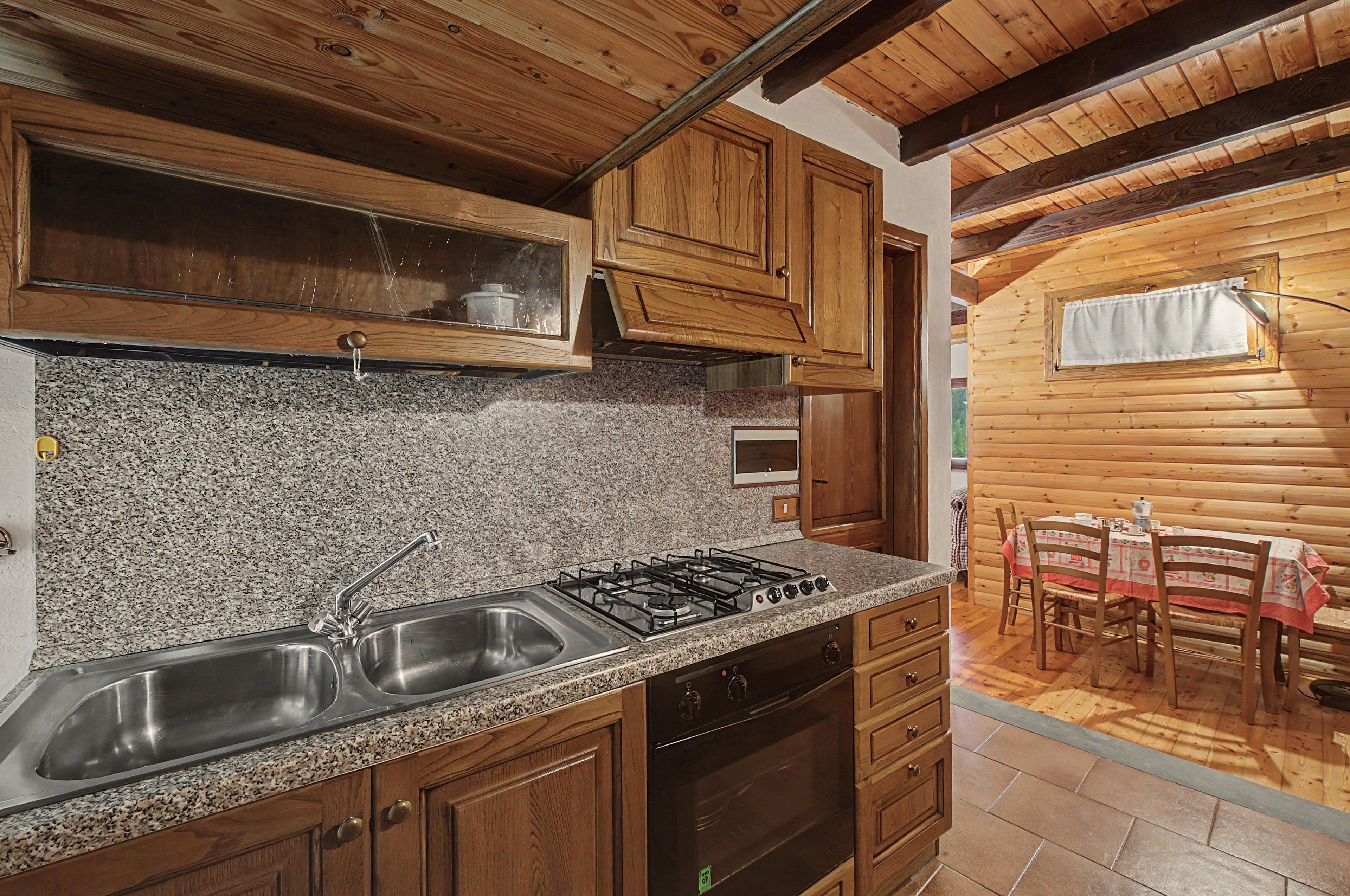 A kitchen with granite countertops, stainless steel appliances, wooden cabinets, and a dining area with a table and chairs.