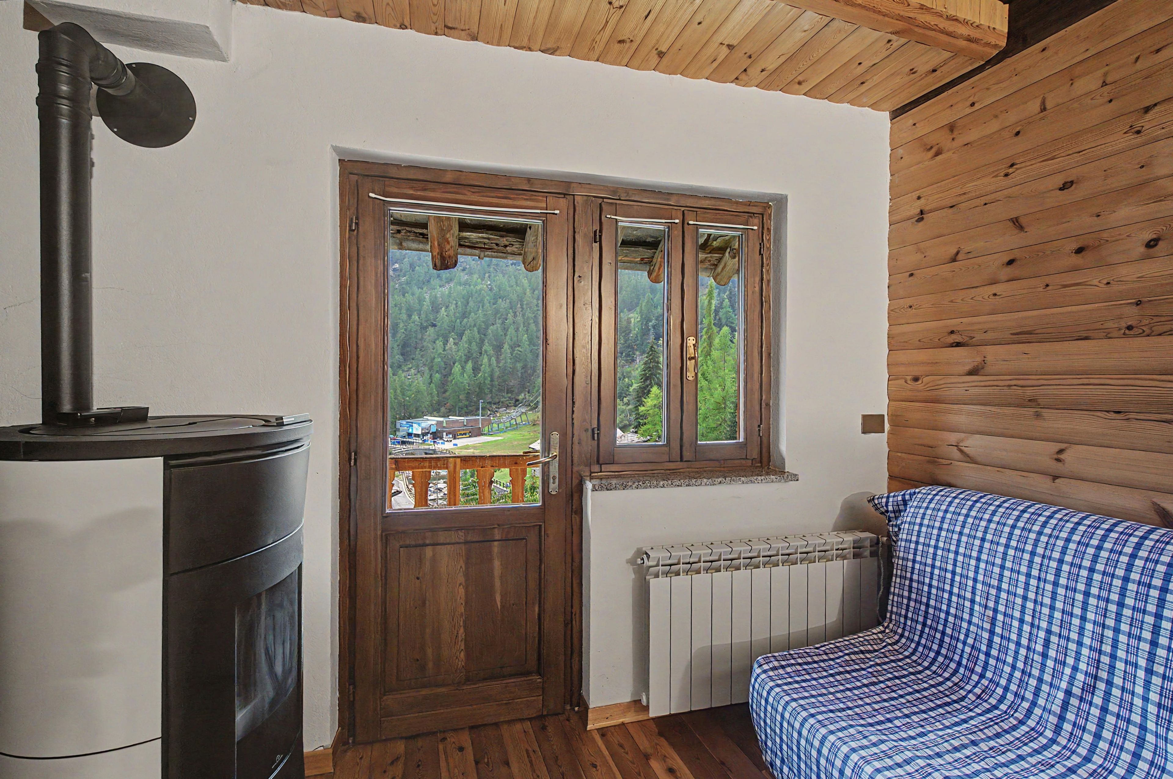 Une pièce avec une porte en bois, un radiateur, un canapé et un poêle.