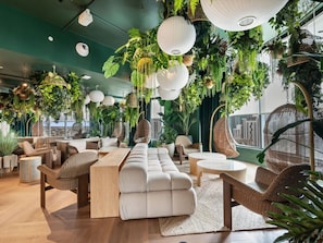 Ein stilvoller Lounge-Bereich mit Sitzgelegenheiten, hängenden Pflanzen und Blick auf die Stadt.