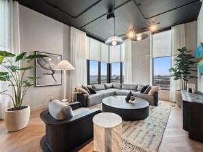 A modern living room with a sectional sofa, round coffee table, and potted plants. - 501 First #2802 Miami Luxury Downtown Escape (Miami)