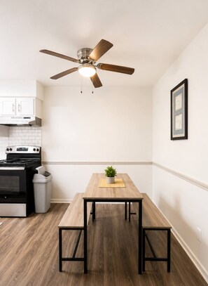 Una cocina moderna con una mesa de madera, un ventilador de techo y una estufa.