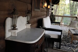 A wooden cabin interior with a marble countertop, two white cushioned chairs, and a table. - Lucky Otter: Cozy + Artsy Lakeside Log Cabin (Mount Nebo)
