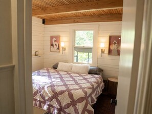 A bedroom with a large bed, a window, and wall-mounted lamps. - Lucky Otter: Cozy + Artsy Lakeside Log Cabin (Mount Nebo)