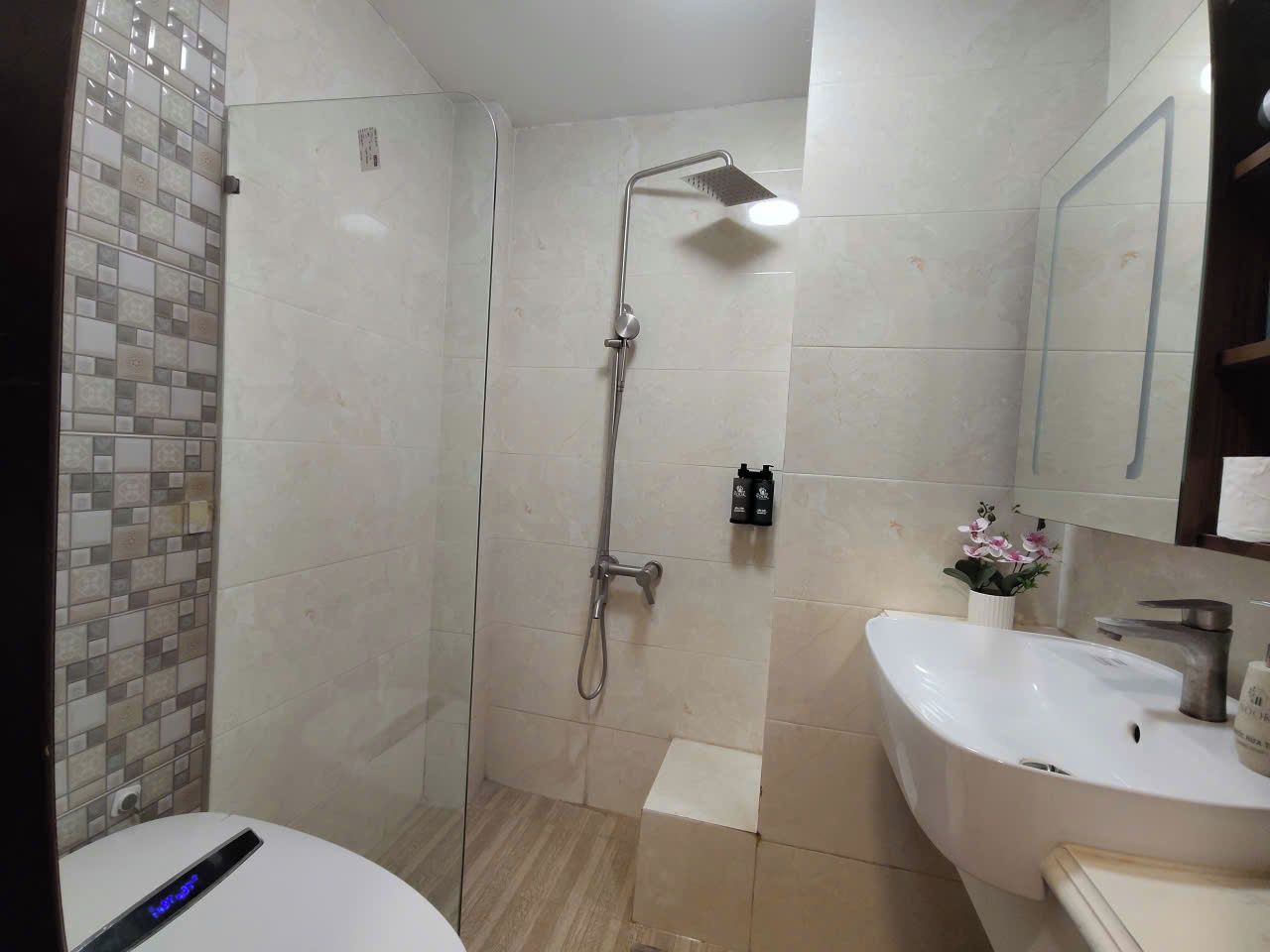 Een badkamer met een douche, een wastafel en een toilet.