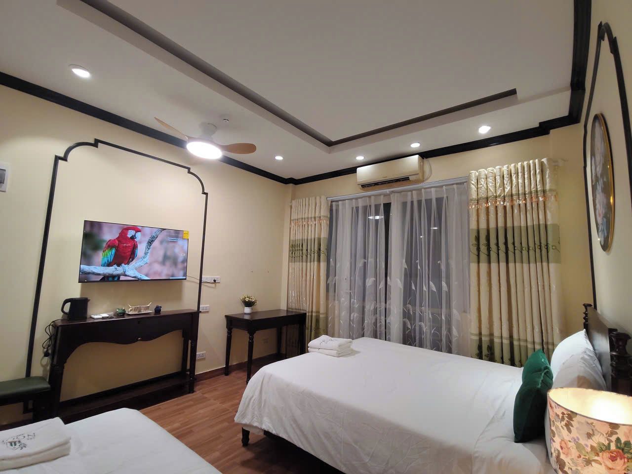 Una habitación de hotel con cama, escritorio, televisor y ventana con cortinas.