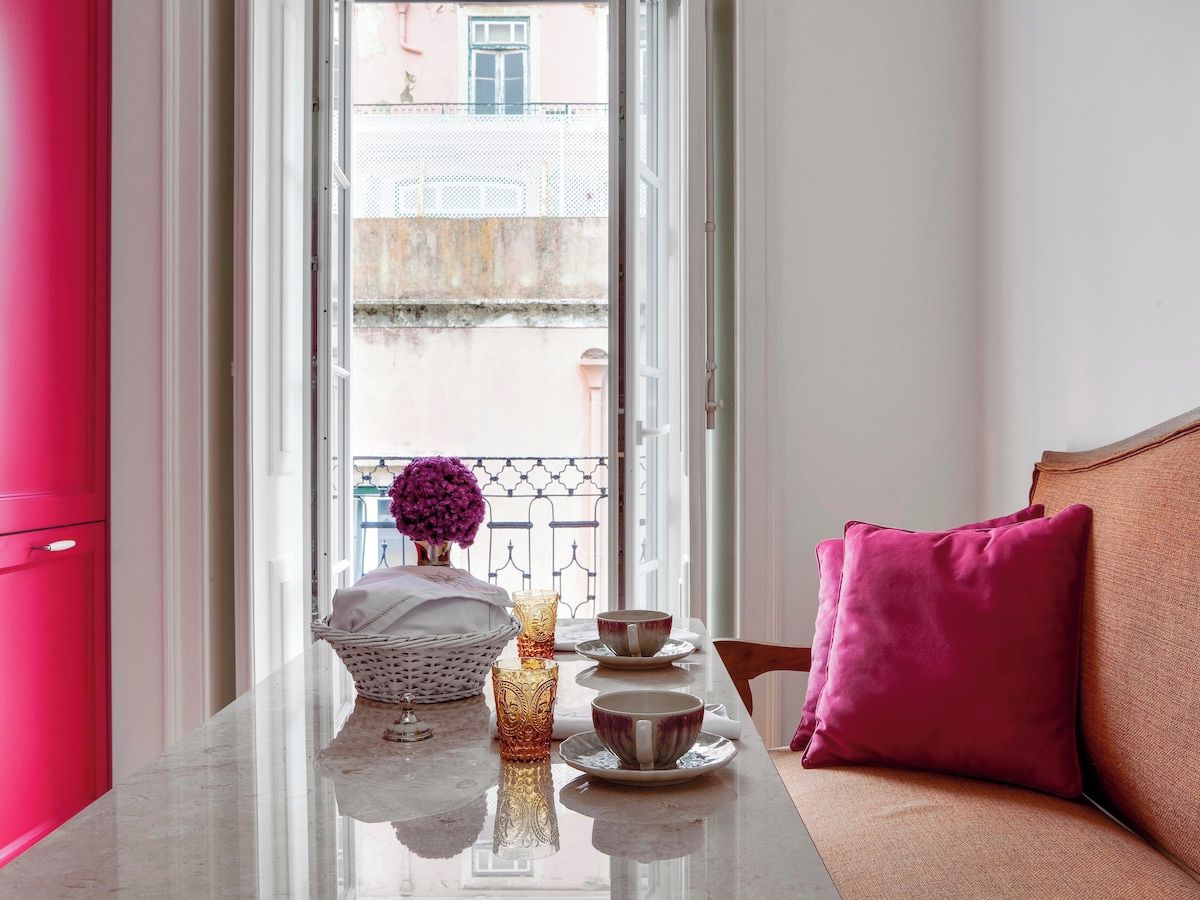 Une pièce avec une table mise pour le thé, un panier en osier et un vase rempli de fleurs.