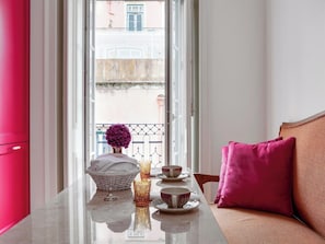 Ein Zimmer mit gedecktem Tisch für Tee, einem Korbwannen und einer Vase mit Blumen.