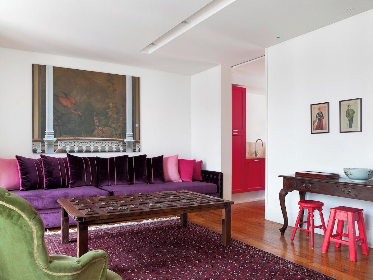 Un salon moderne avec un canapé violet, une table basse et des tabourets rouges.