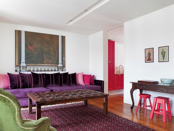 Ein modernes Wohnzimmer mit einem violetten Sofa, einem Couchtisch und roten Hocker.