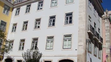 Un edificio de varios pisos con fachada blanca, numerosas ventanas y balcones.