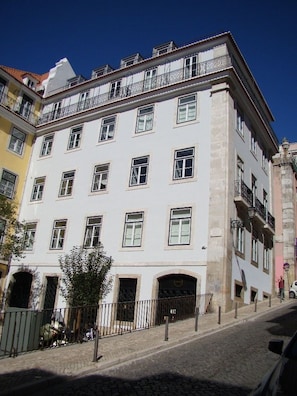 Un edificio de varios pisos con fachada blanca, numerosas ventanas y balcones.