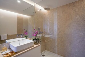 Ein modernes Badezimmer mit einem Doppelwaschbecken, einer Glasdusche und Zierorchideen.
