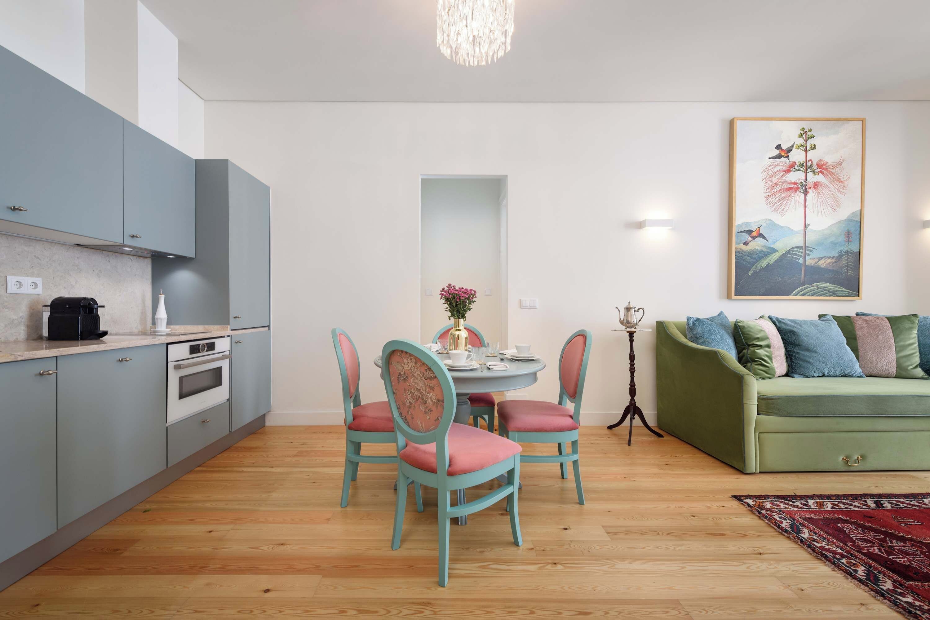 Espaço compacto com cozinha compacta, área de refeições e sofá verde.
