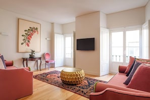 Uma sala de estar moderna com uma mesa de centro de madeira, um sofá vermelho, um tapete estampado e um quadro na parede.