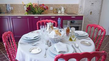 A dining table set with plates, glasses, and cutlery, surrounded by pink chairs.