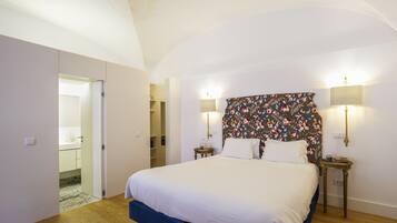 A bedroom with a large bed, two bedside lamps, a floral headboard, and a wardrobe.
