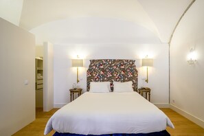 Un dormitorio con una cama grande, dos mesitas de noche, un armario y un cabecero con motivos florales.