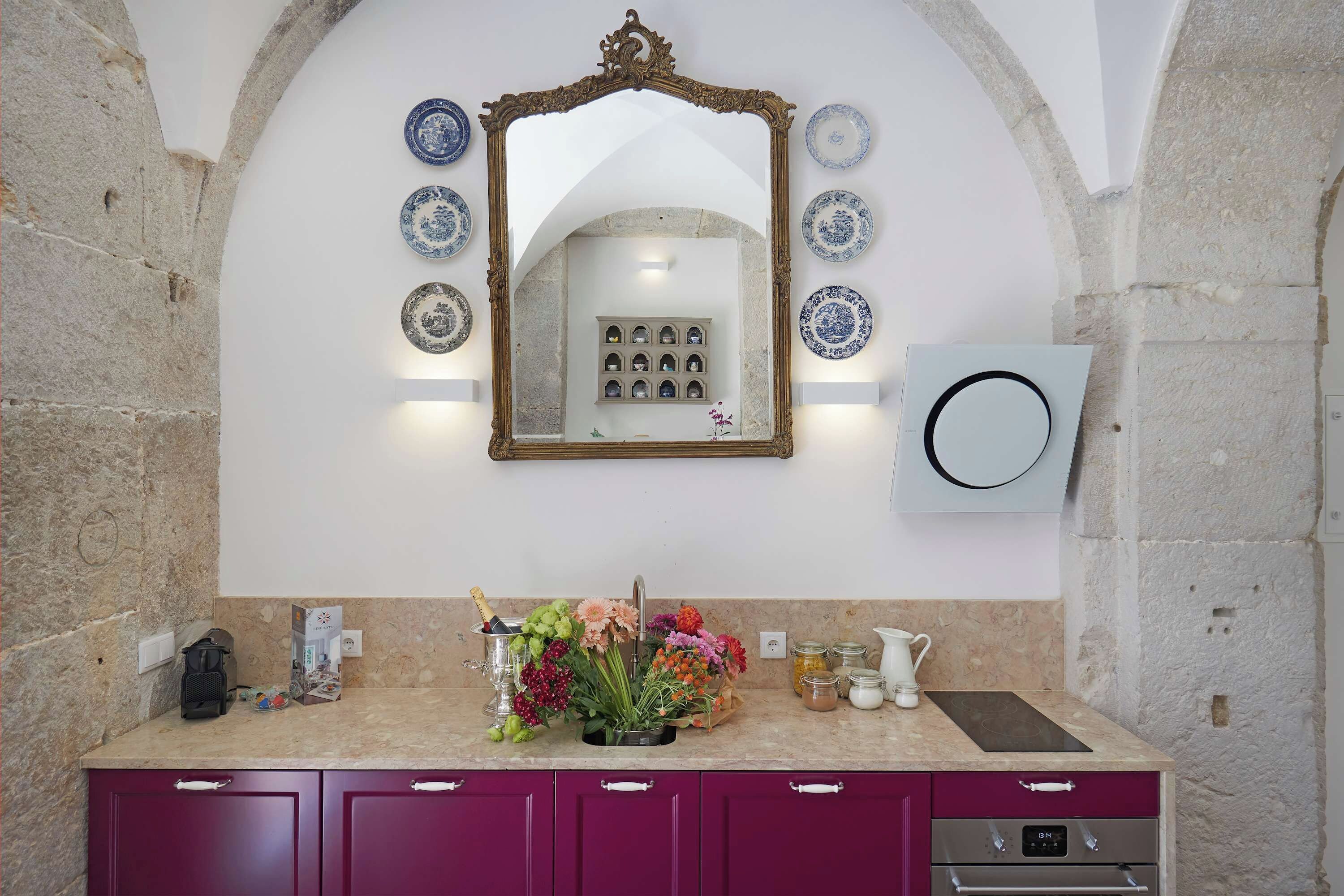 A bathroom with a marble countertop, a sink, a mirror, and a selection of decorative plates.