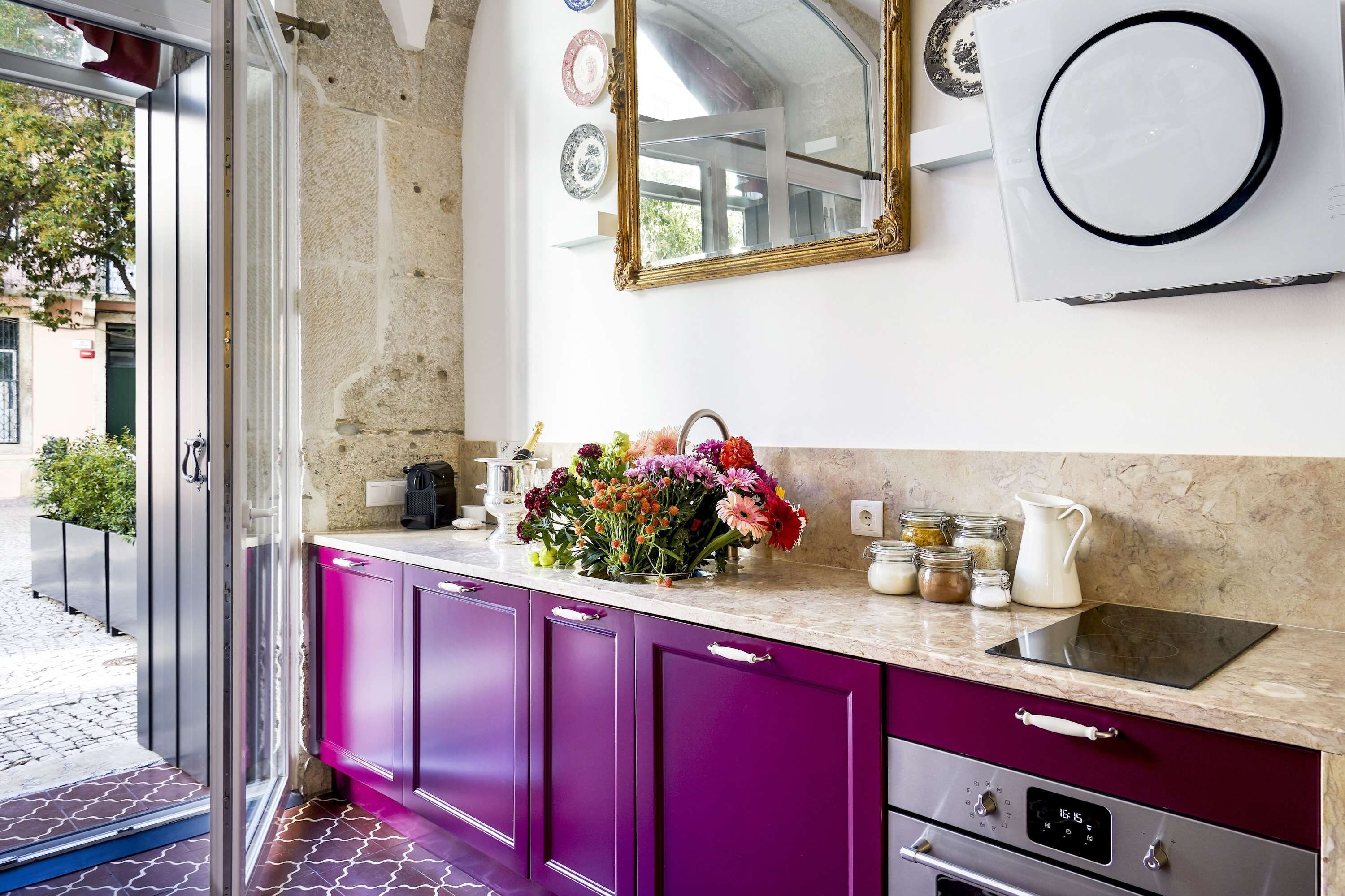 Eine moderne Küche mit violetten Schränken, einer Marmorarbeitsplatte und einem eingebauten Backofen.