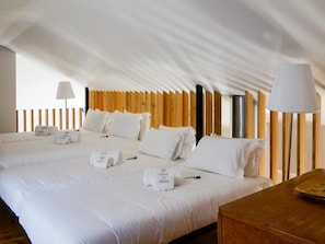 Een hotelkamer met twee bedden, een houten hoofdeinde, een nachtkastje en een lamp.