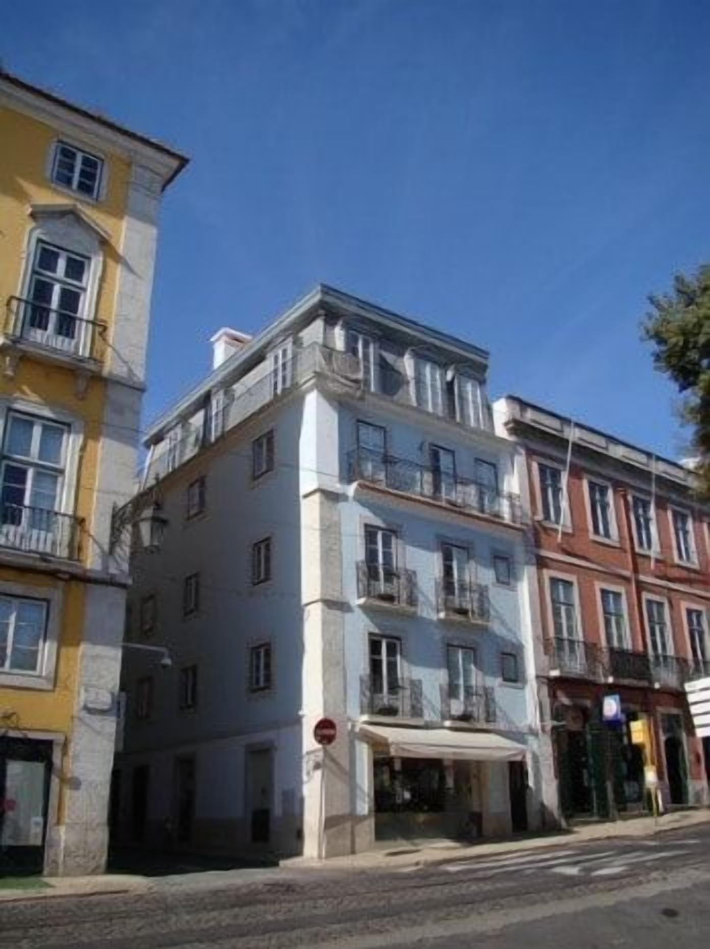 Ein mehrstöckiges Gebäude mit Balkonen, einem Eingang im Erdgeschoss und einem sichtbaren Schaufenster.