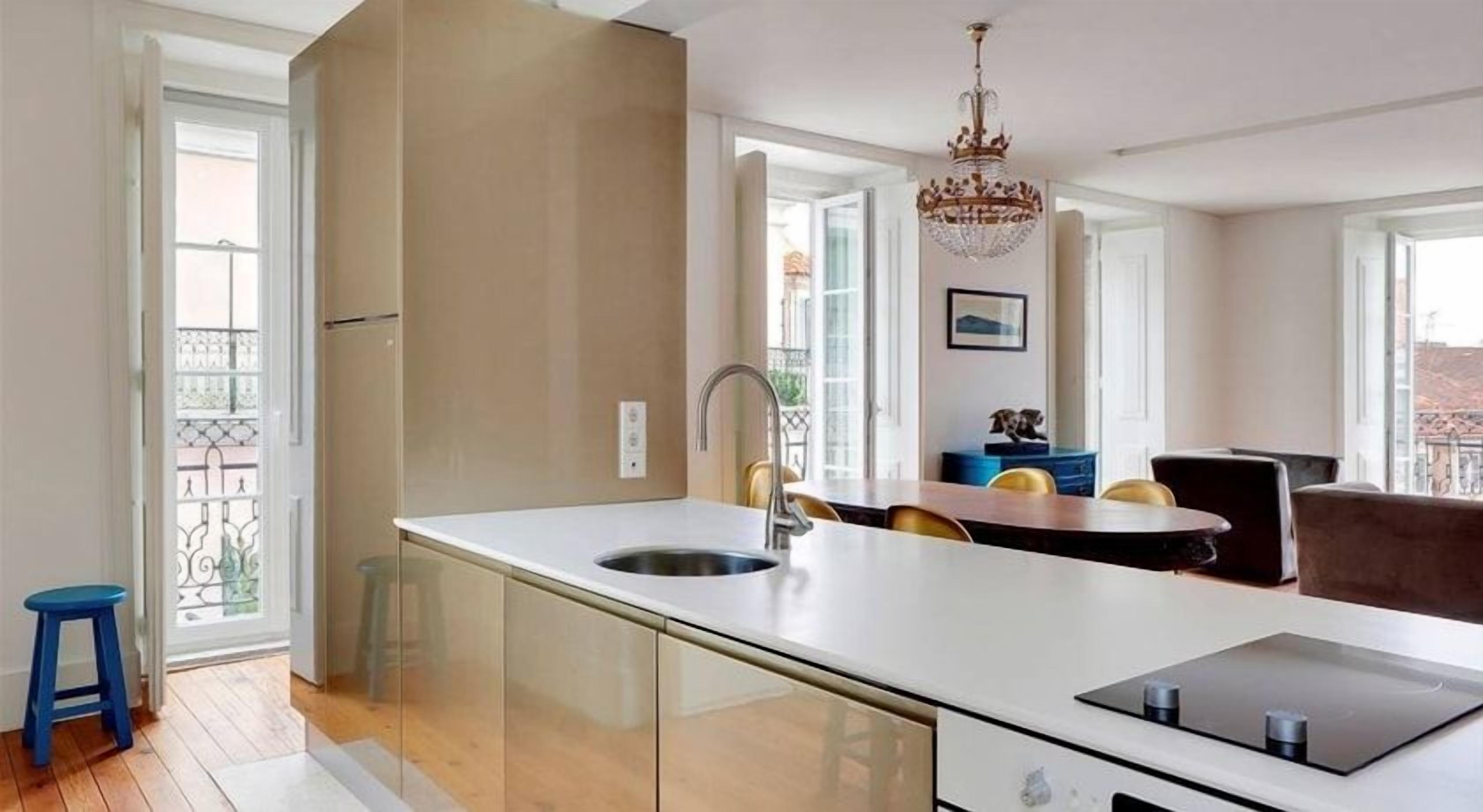 A modern kitchen with a central island, a sink, and a dining area with chairs.