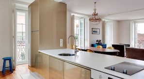 A modern kitchen with a central island, a sink, and a dining area with chairs. - Lisbon Duplex Apartment with 2 Bedrooms & Balcony (Lisbon)