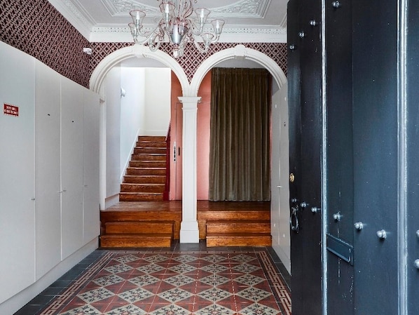 A hallway with a wooden staircase, white walls, and a patterned floor. - Lisbon Duplex Apartment with 2 Bedrooms & Balcony (Lisbon)