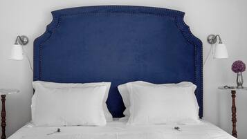 A bed with a blue upholstered headboard, white bedding, and two bedside lamps.