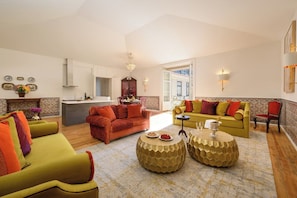 A spacious living area with a kitchen in the background, a yellow sofa, a red sofa, and a round gold coffee table. - Rossio View One-Bedroom Apartment in Lisbon (Lisbon)